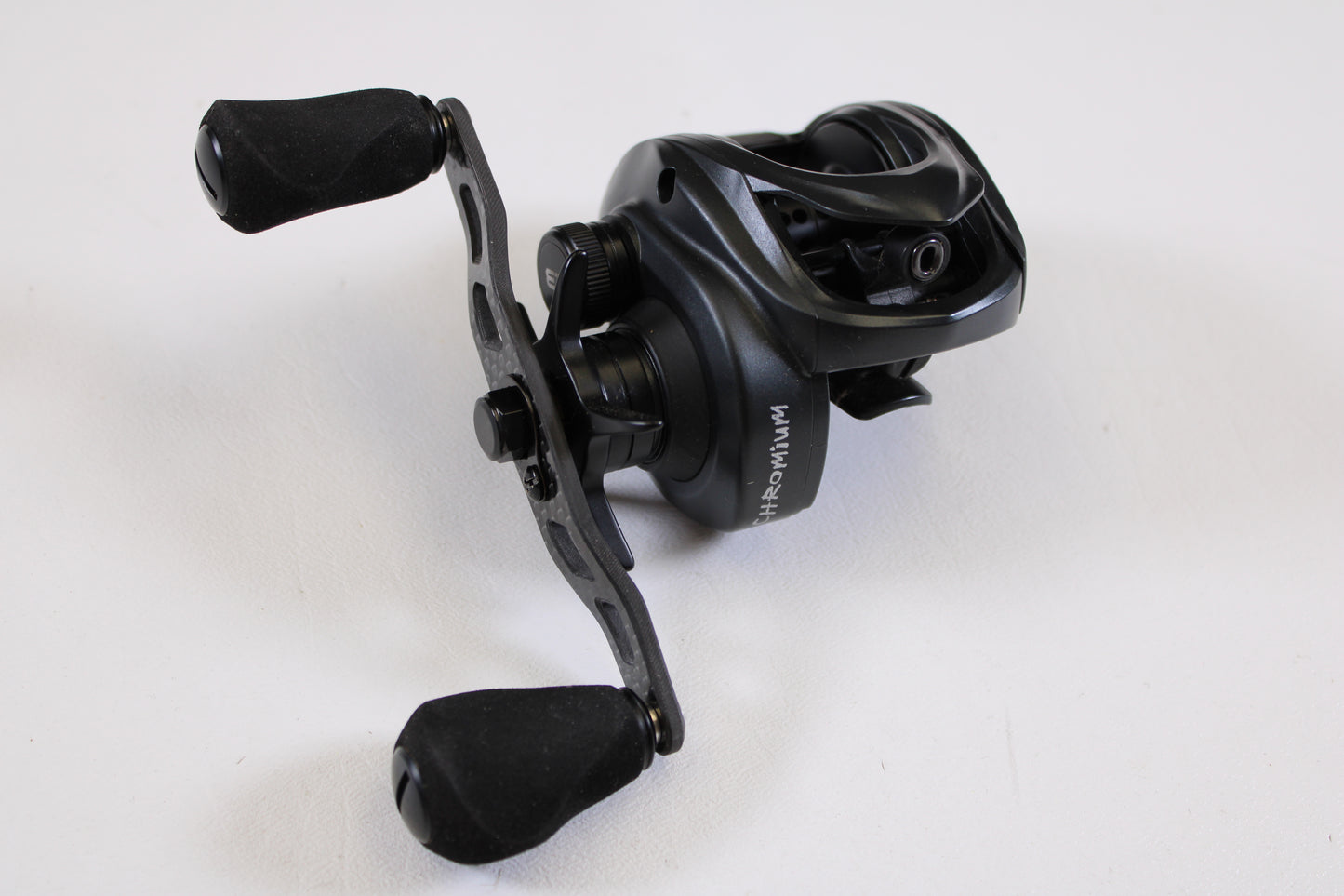 A Kistler Chromium KCR-BK-R173 7.3:1 RH used casting reel in excellent condition, featuring two rubberized handles and stylish metallic and matte black finishes, is shown on a white surface—ideal for savings with our Rod and Reel Trade-In Program.