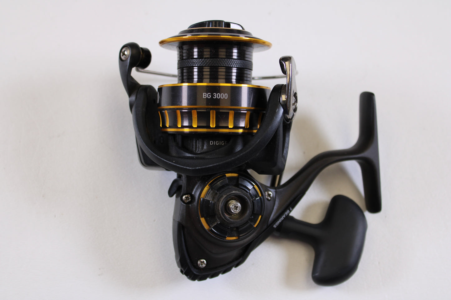 The Daiwa BG BG3000 5.6:1 Used Spinning Reel, in excellent condition, is shown in black and gold against a plain white background. This Daiwa reel features a rotating handle and detailed mechanics—ideal for your next trade-in.
