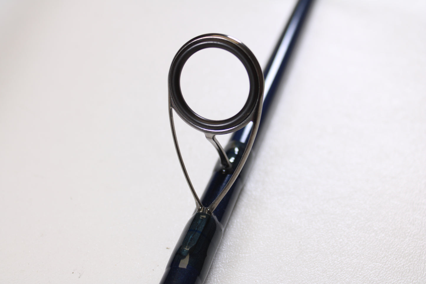 Close-up of a guide ring on a St. Croix Seage SES90MMF2 9'0" Medium 2 Piece Used Spinning Rod (Excellent Condition), available through our Rod and Reel Trade-In Program for store credit. Plain light background.