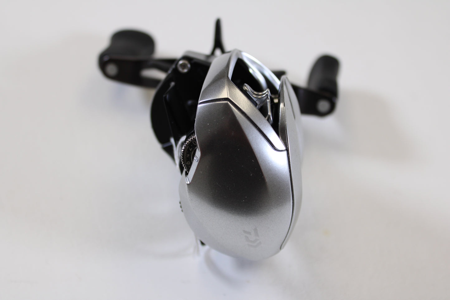 A close-up of a Daiwa Zillion ZLNSVG100 6.3:1 RH used casting reel in excellent condition, featuring silver construction and black handles—ideal for those exploring our rod and reel trade-in program.