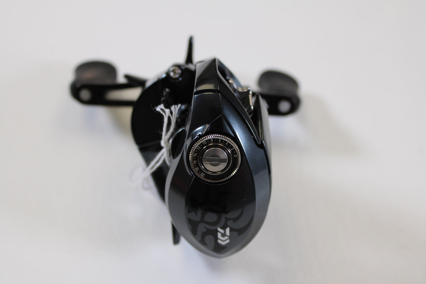 A close-up of a Daiwa Tatula SV 70 Used Casting Reel in excellent condition, featuring a black finish with silver details and handle on a white surface. Trade in your used gear for store credit with our Rod and Reel Trade-In Program.
