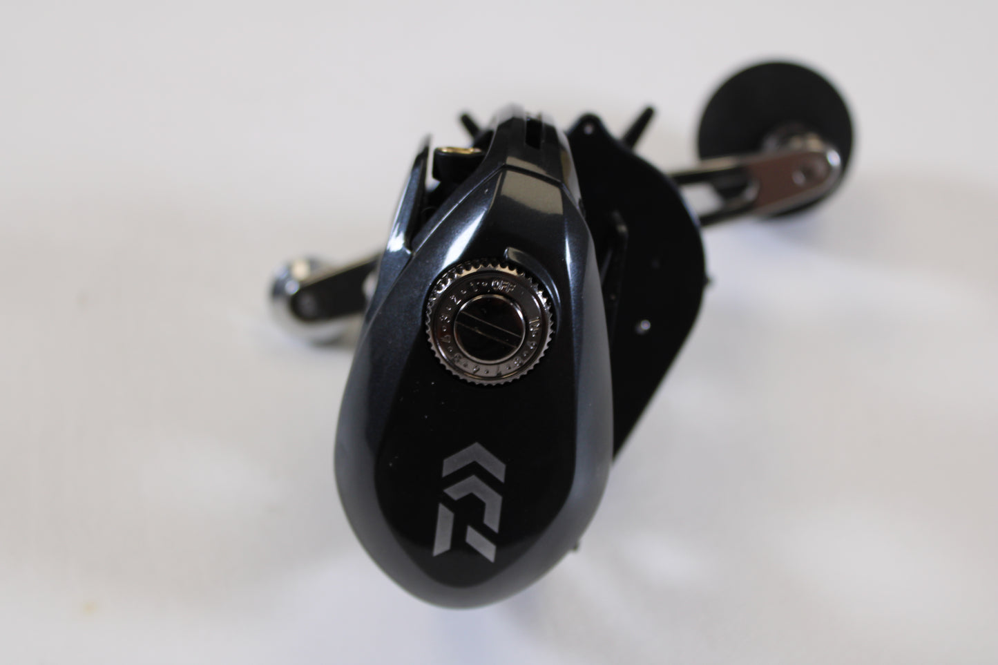 Close-up of a Daiwa Lexa 300 LX 300HL-P 7.4:1 LH Used Casting Reel in excellent condition with a silver adjustment knob and white geometric logo—perfect for upgrading through our Rod and Reel Trade-In Program for store credit. White background shown.