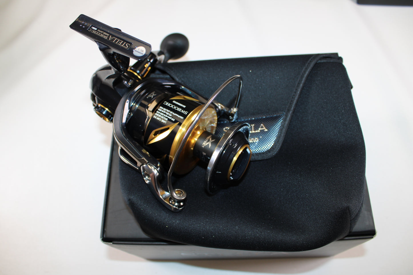 A Shimano Stella SW C STLSW18000HGC used spinning reel in mint condition by Shimano is shown on its case and box against a white background—ideal for those interested in our Rod and Reel Trade-In Program.