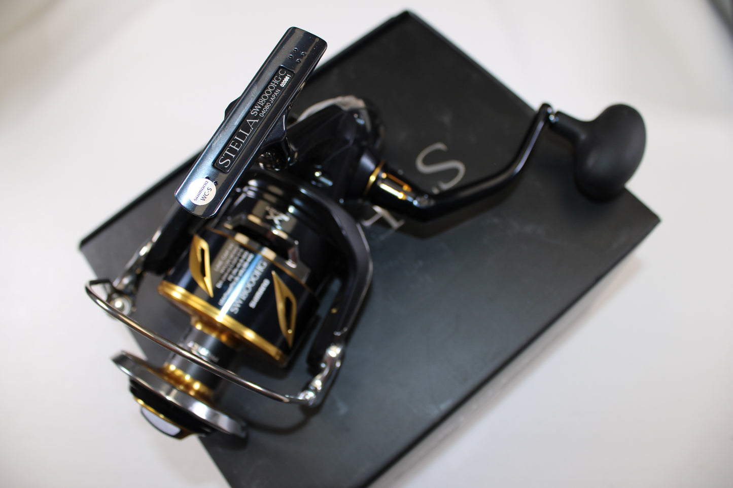 A Shimano Stella SW C STLSW18000HGC Used Spinning Reel in mint condition, shown atop its original black box—ideal for upgrade with our Rod and Reel Trade-In Program to earn store credit on your used gear.