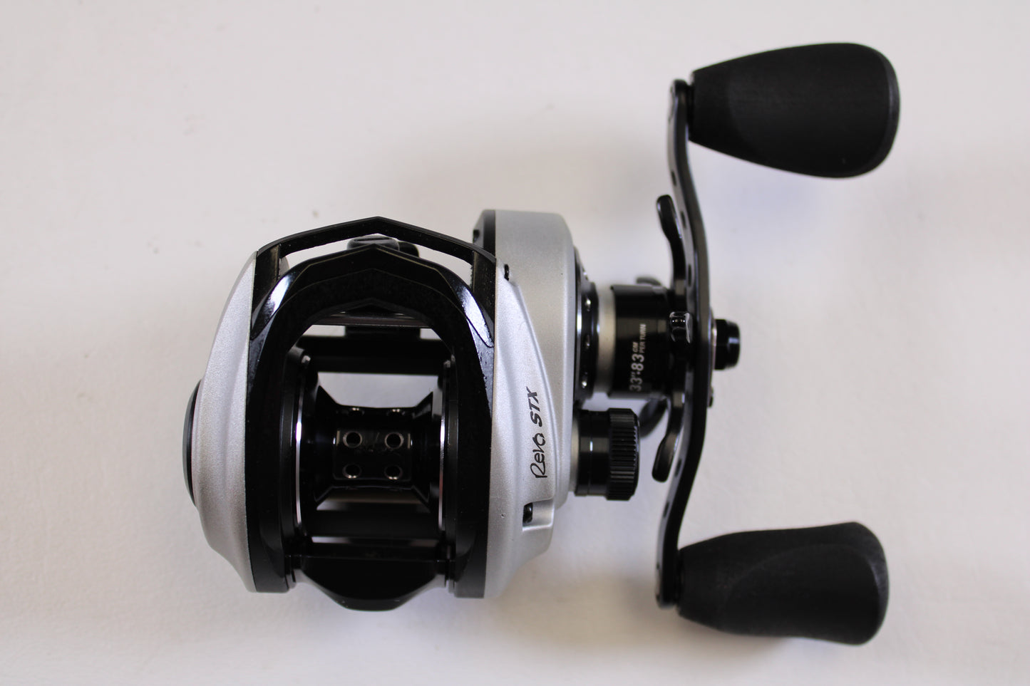 An Abu Garcia Revo STX Gen 4 REVO3STX-SHS 8.0:1 RH casting reel in excellent used condition, featuring a silver and black design with dual black handles, is ideal for our Rod and Reel Trade-In Program for store credit.