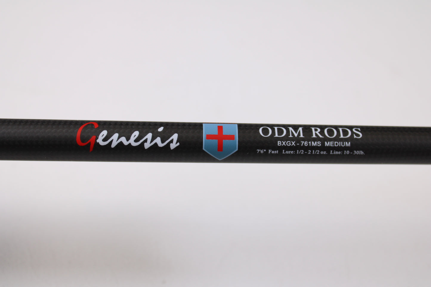 Close-up of an ODM Rods Genesis Inshore BXGX 761MS 7'6" Medium used spinning rod with blue and red shield logo. Specs: Fast action, 1/2–2 1/2 oz., line rating 10–30 lb. Ideal for anglers using our rod and reel trade-in program.