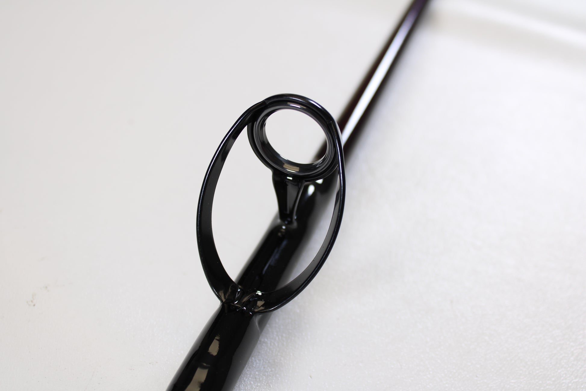 Close-up of a St. Croix Mojo Salt MSWC76MHMF 7'6" Medium Heavy used casting rod guide on a smooth, light surface. This mint condition rod is ideal for anglers trading in gear for store credit with our Rod and Reel Trade-In Program.