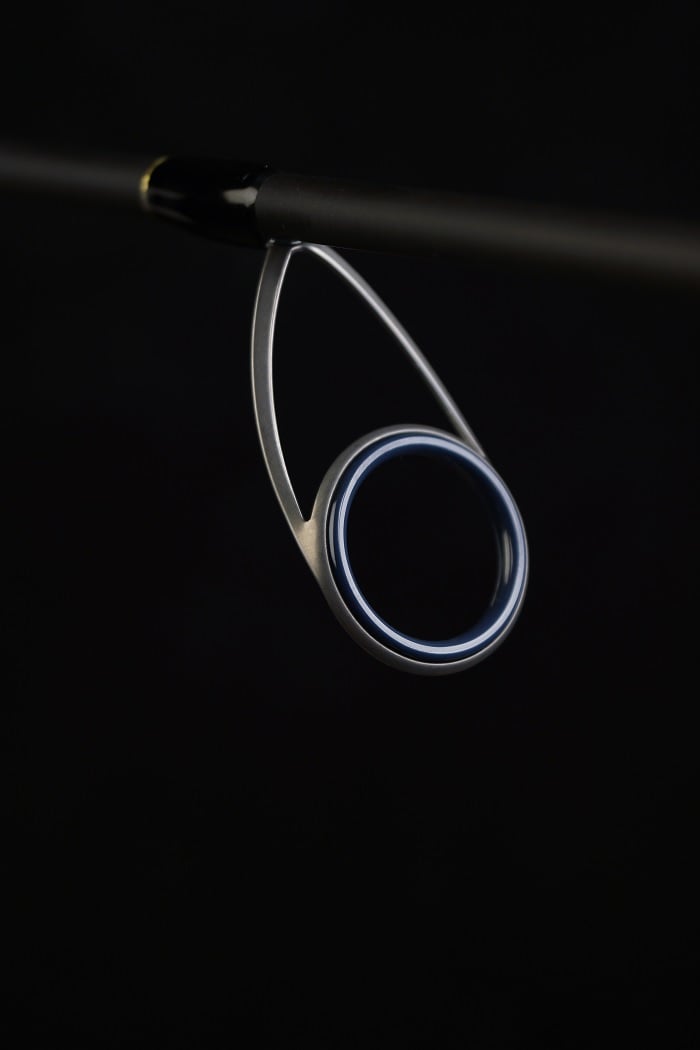 Close-up of the Falcon Cara Spinning Rod Medium Spin 7'0" (CS-4-17) guide against a dark background, showcasing its metallic ring and premium Fuji component support structure.