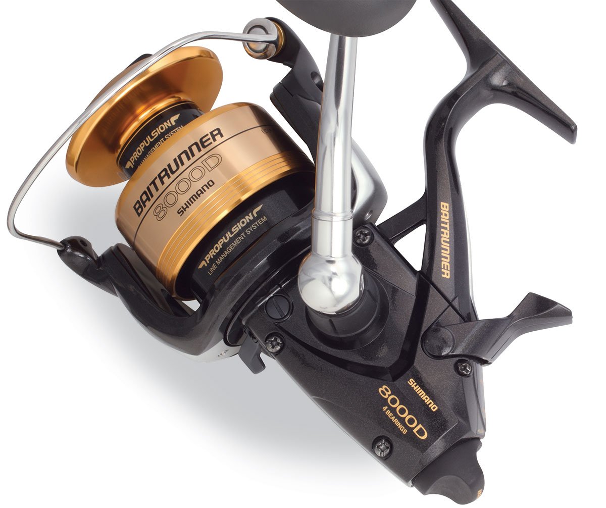 Close-up of a Shimano Baitrunner BTR8000D Spinning Fishing Reel, showing its gold and black design, Shimano branding, intricate parts, and the advanced Propulsion Line Management System.