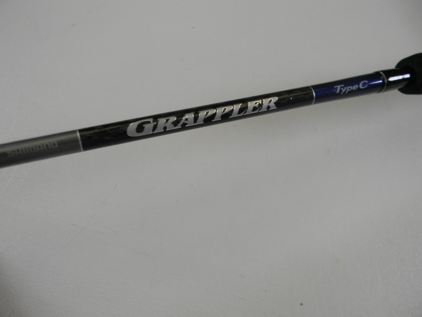 A close-up of the Shimano Grappler Type C GRPCS70L 7'0" Light Used Spinning Rod in excellent condition, featuring "GRAPPLER" in bold silver letters—ideal for those looking to upgrade with our Rod and Reel Trade-In Program.