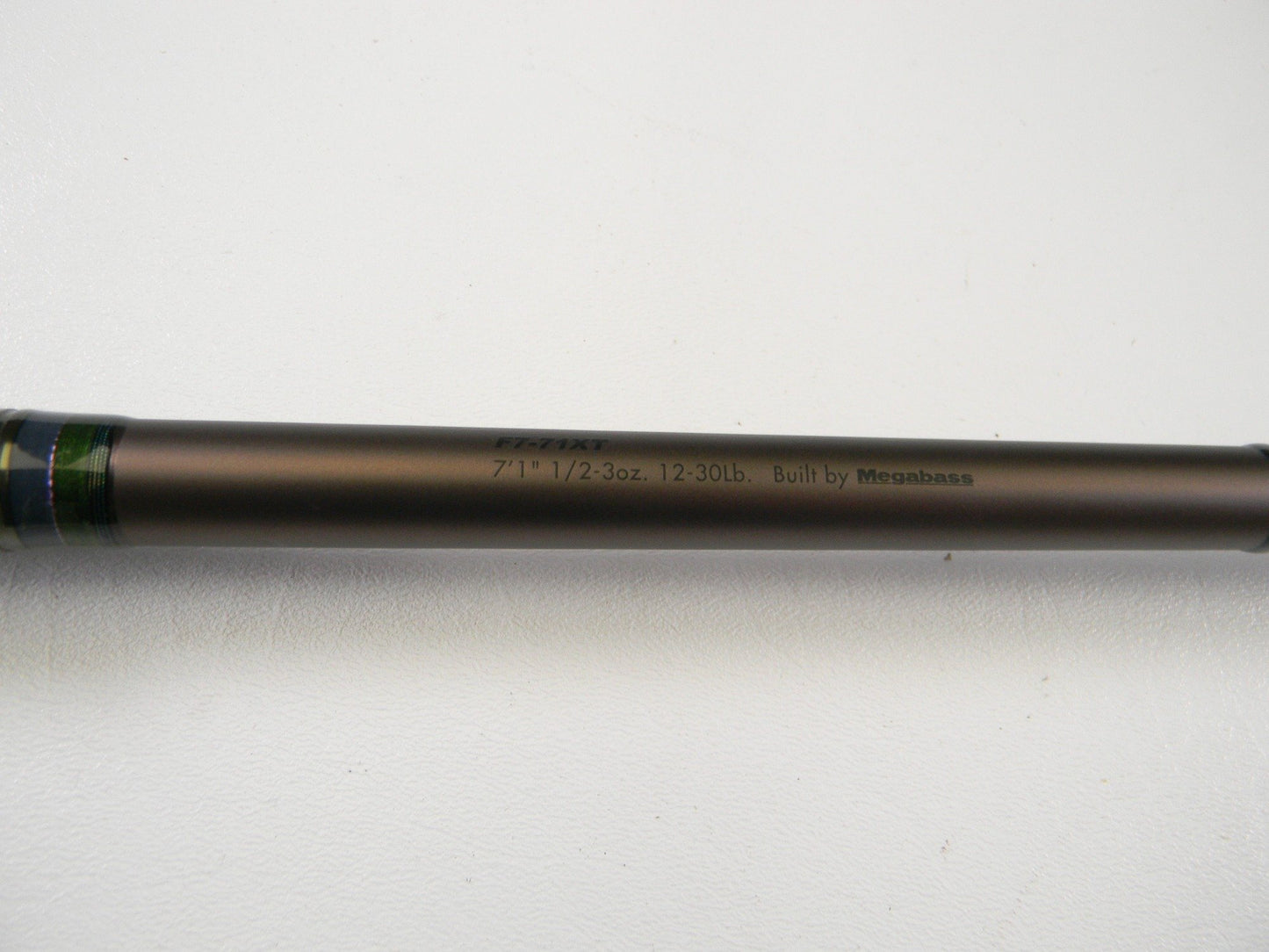 A close-up of the Megabass Orochi X10 F7-71XT Swamp Survivor 7'1" Heavy Casting Rod in excellent used condition, featuring printed specs on a metallic brown shaft—ideal for upgrading your gear or rod and reel trade-ins.