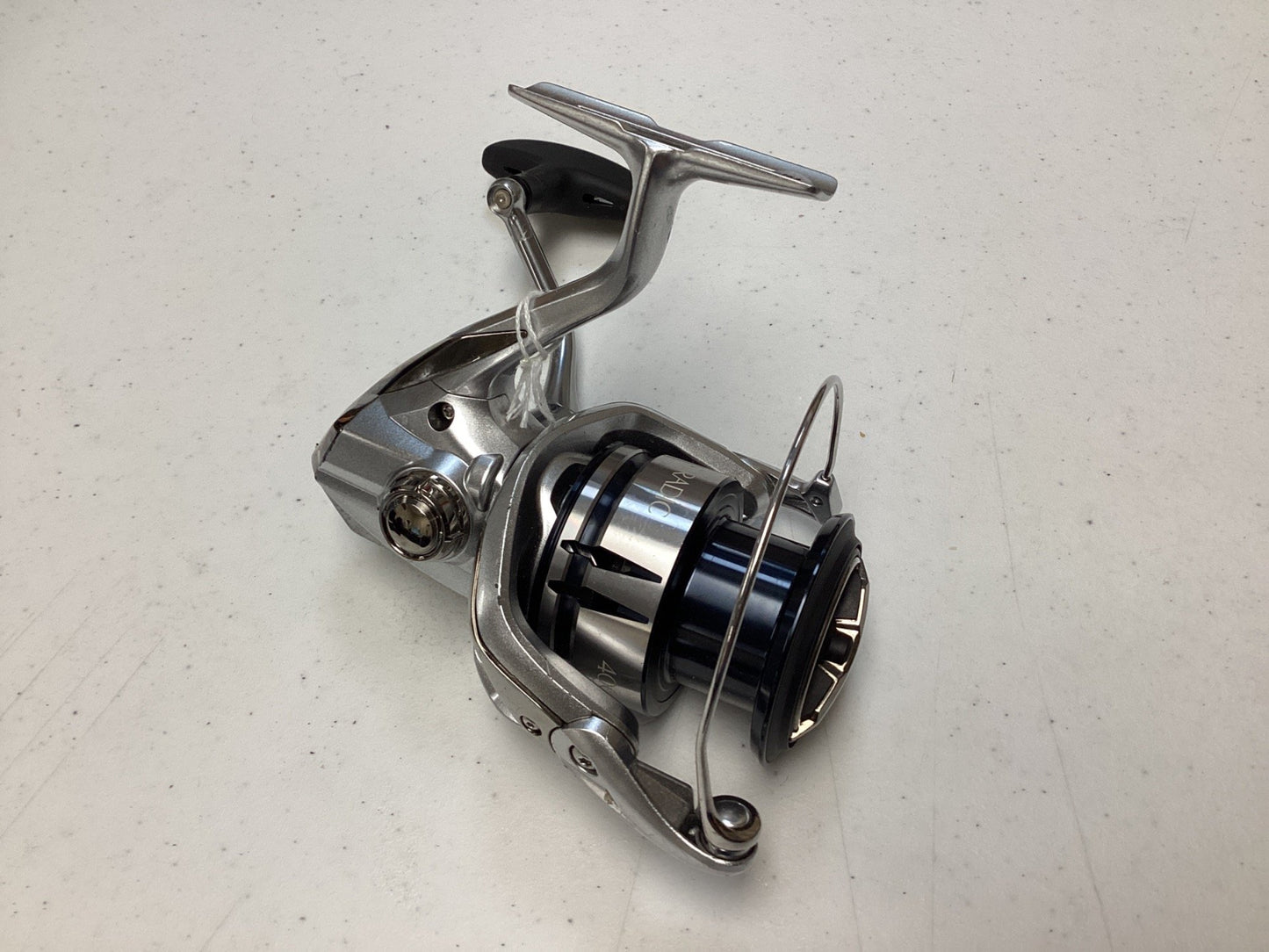 A Shimano Stradic FL ST4000XGFL Used Spinning Reel in very good condition, shown on a white speckled surface, is perfect for our Rod and Reel Trade-In Program—trade in your used Shimano gear for store credit.
