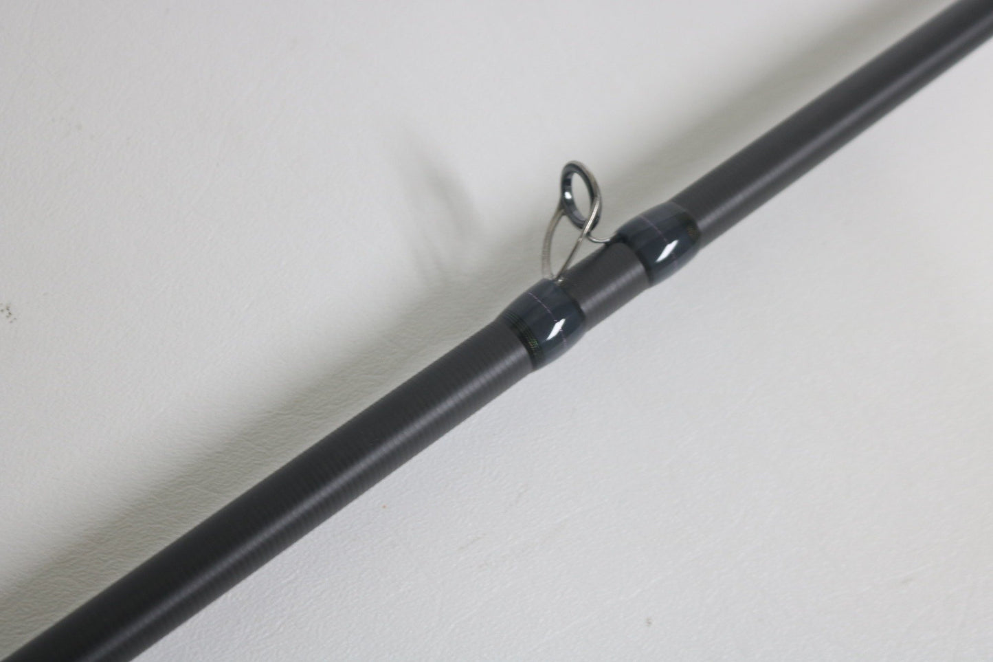 Close-up of a Megabass Destroyer P5 F7.1/2-76X Used Casting Rod in excellent condition, highlighting one of its black line guides against a plain white background.