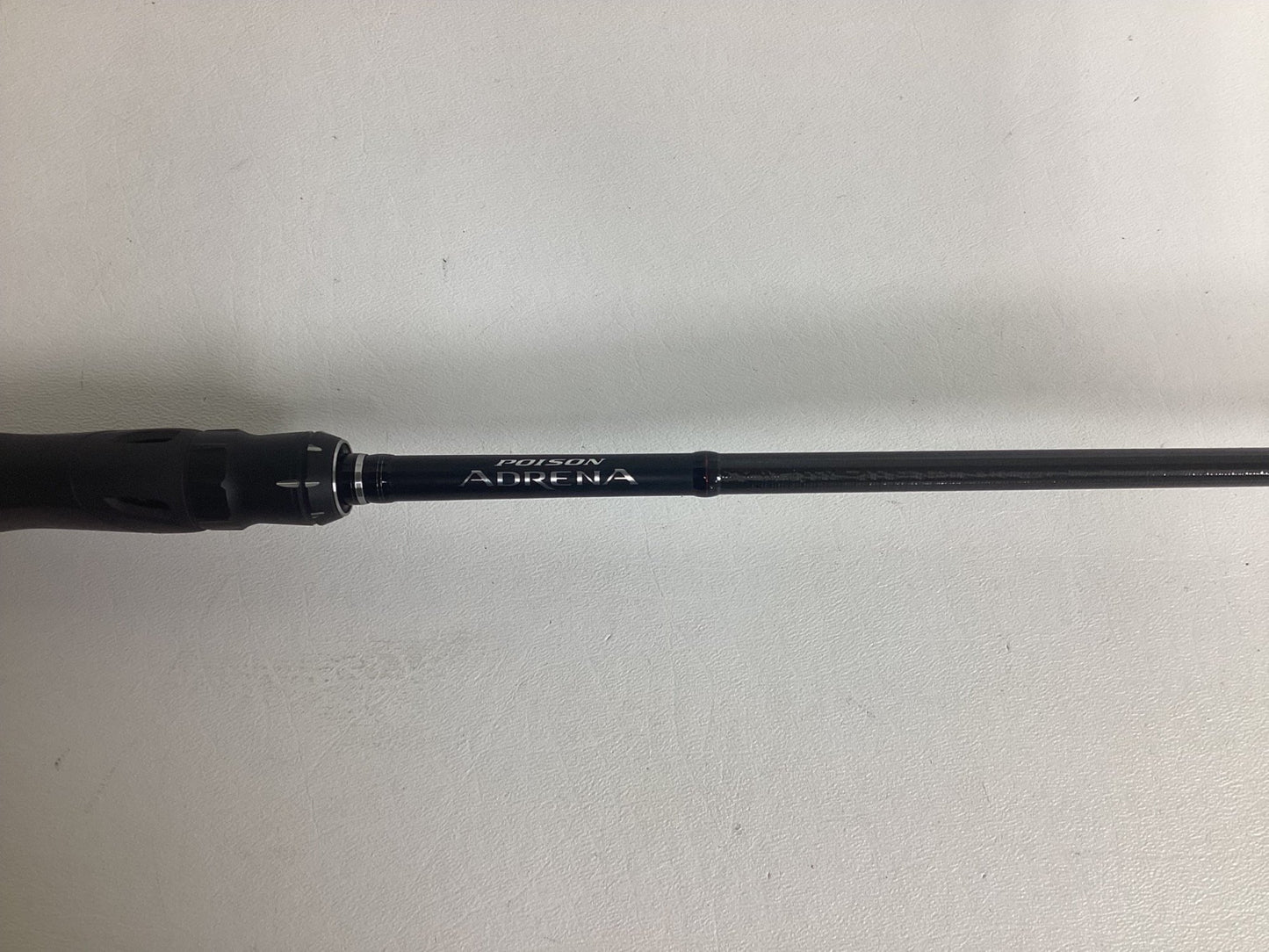 A close-up of a Shimano Poison Adrena PAD267MLA 6'7" Medium Light used spinning rod in excellent condition, shown on a white background—ideal for anyone seeking top-quality pre-owned fishing gear or considering a trade-in.