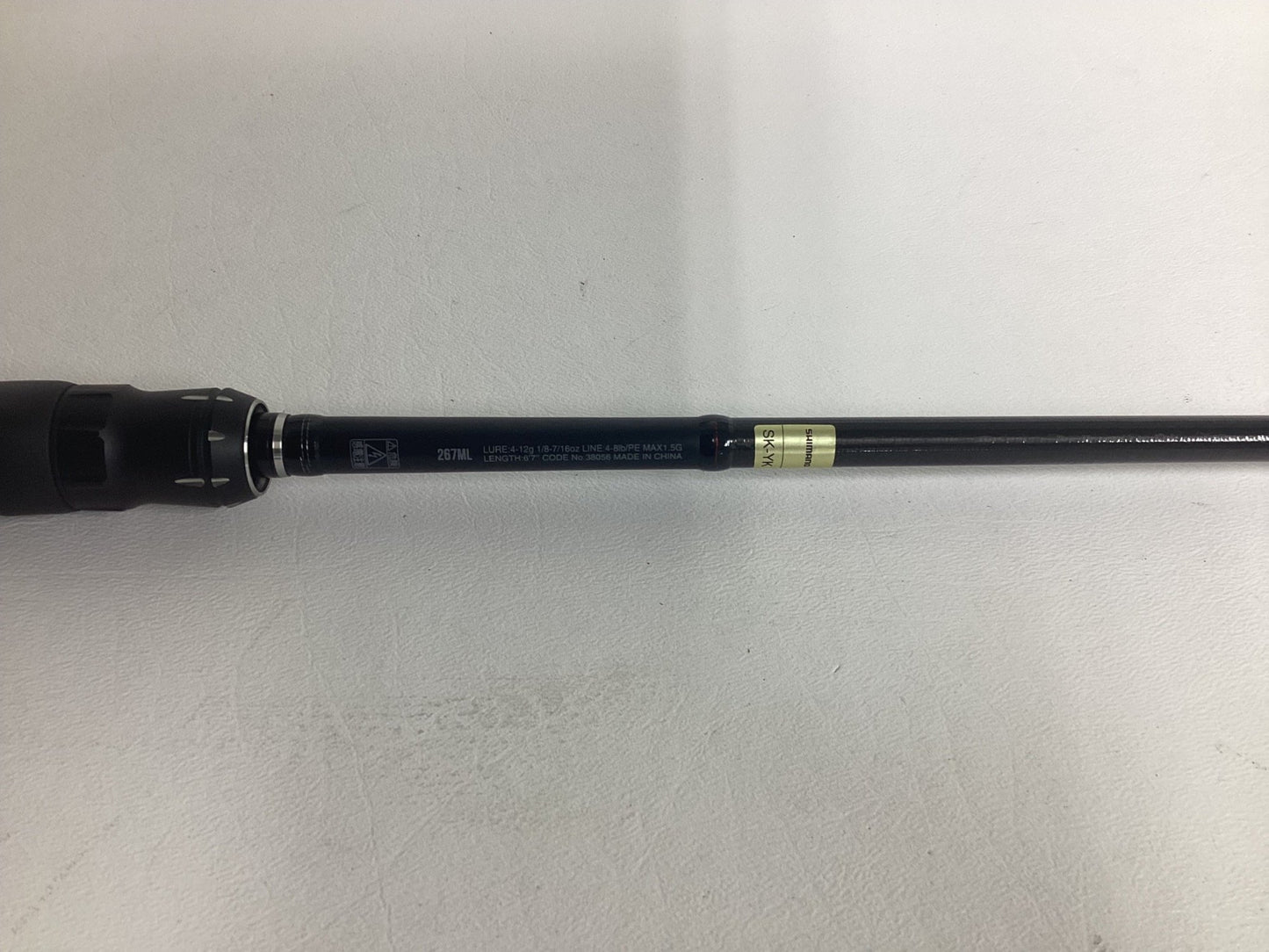 Close-up of a Shimano Poison Adrena PAD267MLA 6'7" Medium Light used spinning rod in excellent condition, showing printed specs on the black handle—great for those seeking quality pre-owned fishing gear by Shimano.