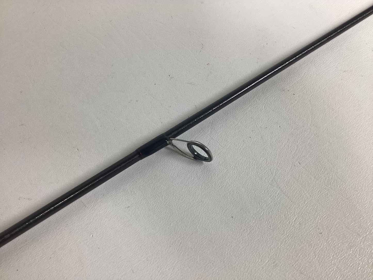 A close-up of the Shimano Poison Adrena PAD267MLA 6'7" Medium Light used spinning rod in excellent condition, showing a metal line guide—great for fishing fans or those trading in gear for store credit.