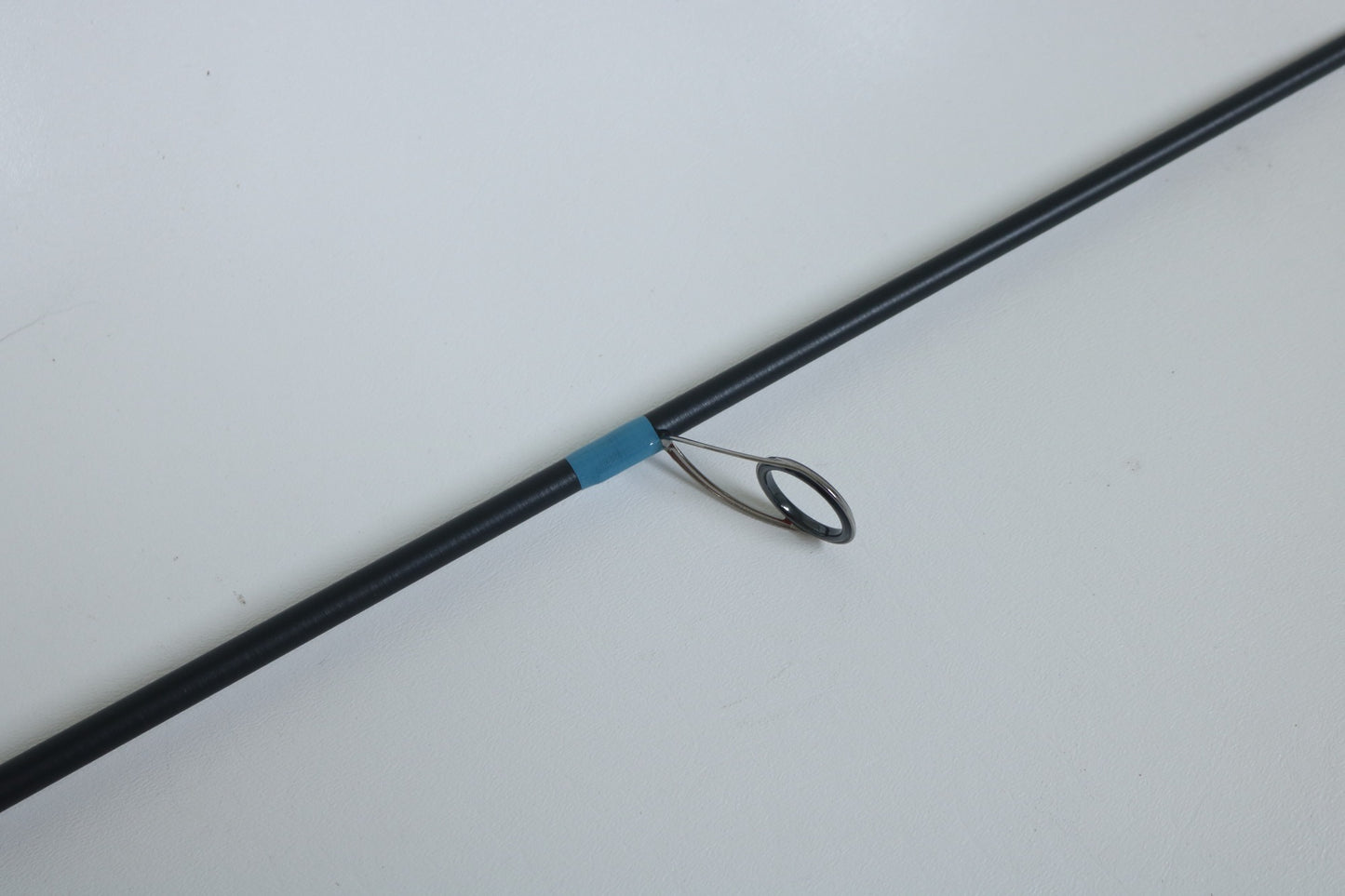 A close-up of a G. Loomis NRX+ 802S JWR Used Spinning Rod in mint condition, featuring a metal guide ring and blue wrap—ideal for anglers seeking quality used gear or exploring our rod and reel trade-in program.
