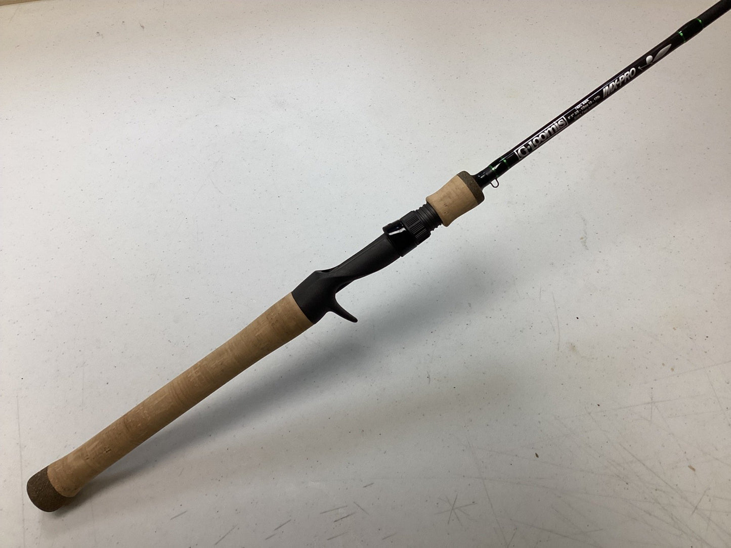 A G. Loomis IMX-Pro 752C SBR Used Casting Rod in excellent condition, featuring a cork handle and exposed reel seat, is displayed diagonally on a white surface—ideal for trade-in upgrades or buying quality used gear with store credit.