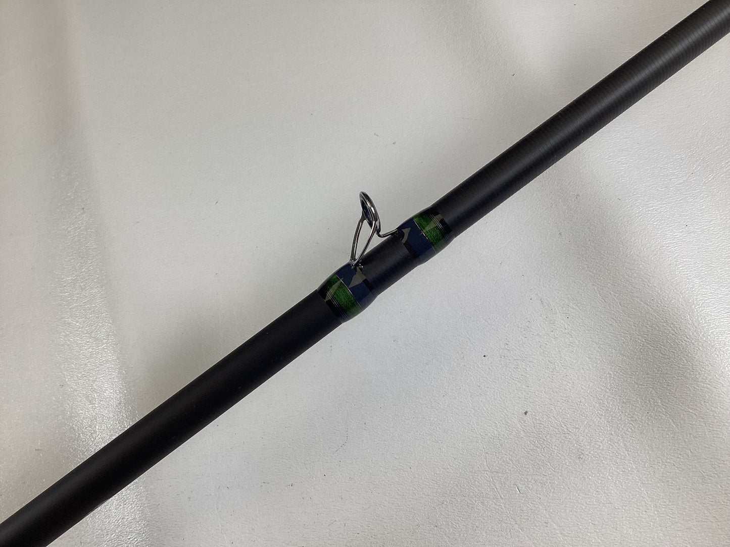 Close-up of a Megabass Orochi X10 F9-710XT Anaconda 7'10" XXH Used Casting Rod in excellent condition features blue and green thread wraps and is eligible for our Rod and Reel Trade-In program for store credit.