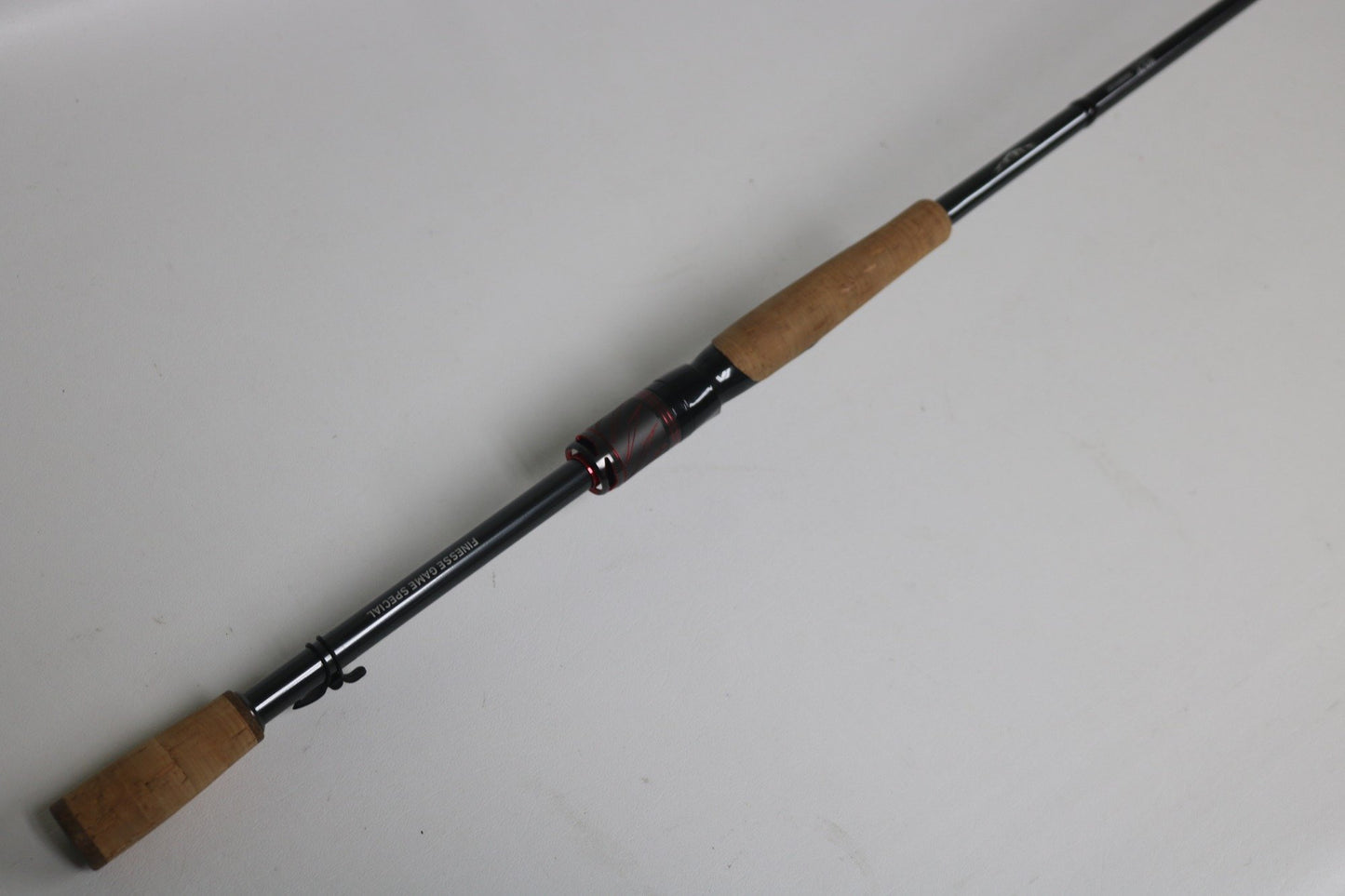The Daiwa Steez AGS STAGS711MLFS 7'1" Medium Light spinning rod, with cork handles and black and red reel seat, rests diagonally on a white background. Trade in your used gear through our Rod and Reel Trade-In Program to earn store credit for your next adventure.