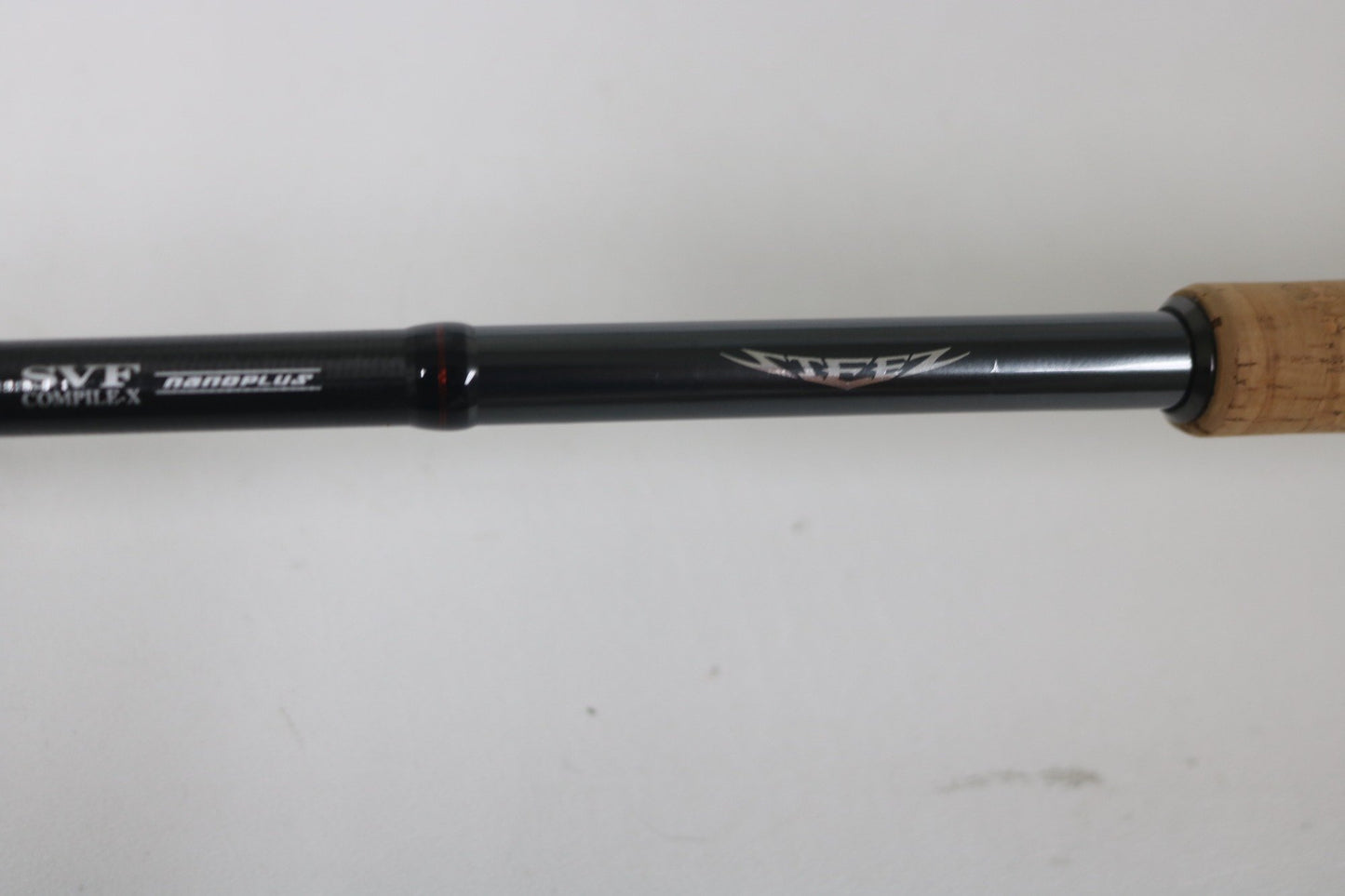 Close-up of a black Daiwa Steez AGS spinning rod with cork handle, featuring "ZEEZ" and "NANOPLUS" near the grip. Ideal for our Trade-In Program, where used gear can be exchanged for store credit. The background is a simple white surface.