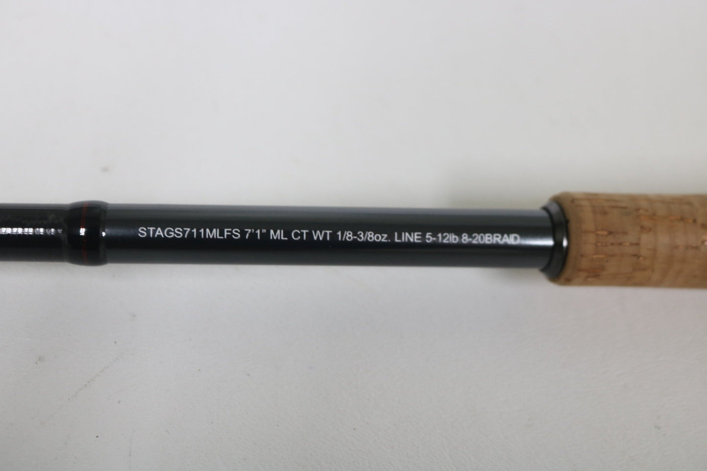 Close-up of a Daiwa Steez AGS STAGS711MLFS 7'1" Medium Light spinning rod, part of our Rod and Reel Trade-In Program. Specs include casting weight 1/8-3/8oz, line 5-12lb & 20 braid. The cork handle enhances the charm of this well-loved used gear in excellent condition. Perfect for earning points!.
