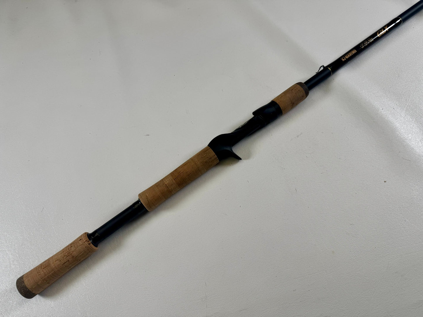 The G. Loomis 24 GLX 954c FPR 7'11" Heavy Used Casting Rod in excellent condition is shown diagonally on a light surface—an ideal choice for those interested in our Rod and Reel Trade-In Program to earn store credit.