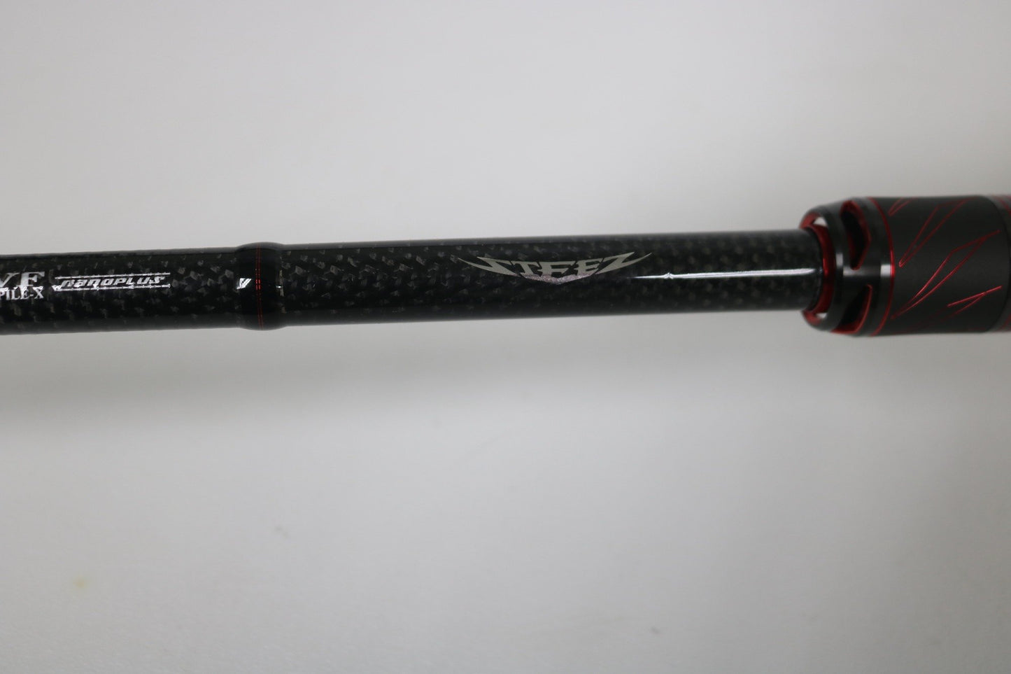 A close-up of the Daiwa Steez AGS STAGS741XHFB casting rod in excellent used condition, featuring black carbon fiber with red accents and "Steez" branding, set against a plain white background.