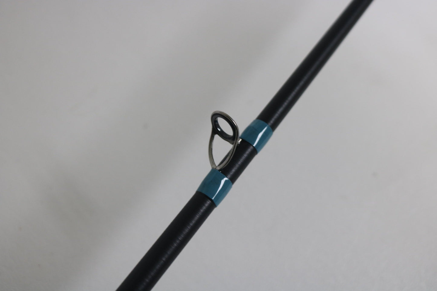 A close-up of the G. Loomis NRX+ 802C JWR Used Casting Rod in excellent condition shows a single metal guide ring with blue wrappings—an ideal choice for those trading up through our Rod and Reel Trade-In Program.