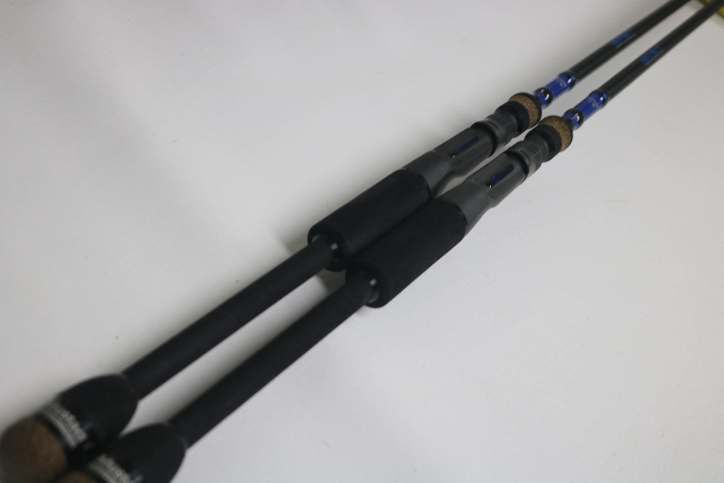 Two Mustad BLF Instinct 7'4" Medium Heavy Casting Rods, used and in very good condition, lie parallel on a white surface—ideal for anglers seeking quality gear through the Nation's Best Rod and Reel Trade-In Program.
