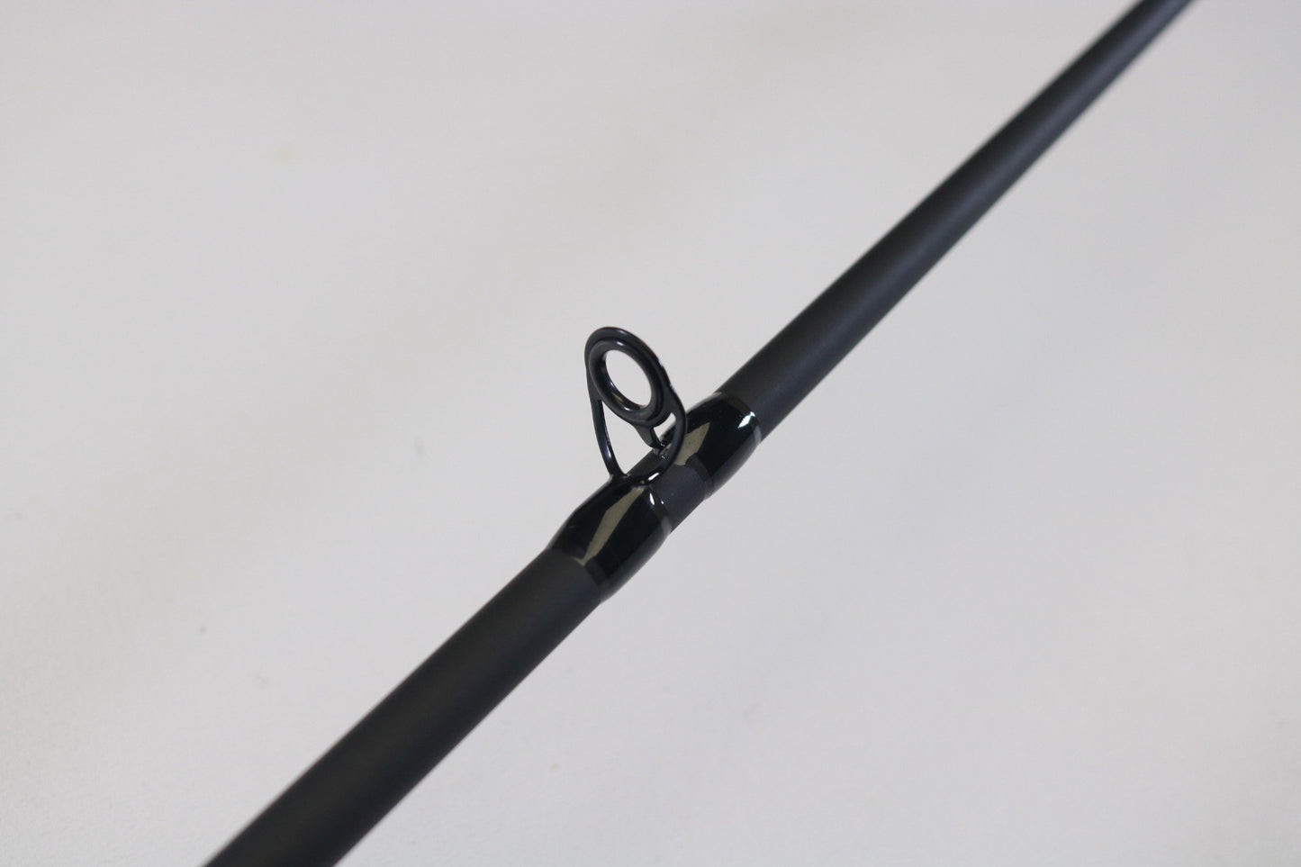 A close-up view of the St. Croix Avid ASFS68MXF 6'8" Medium spinning rod, focusing on a single metal guide ring against a light gray background. Available for store credit or as part of our rod and reel trade-in program, the guide ring is prominently featured with the rod slightly angled.