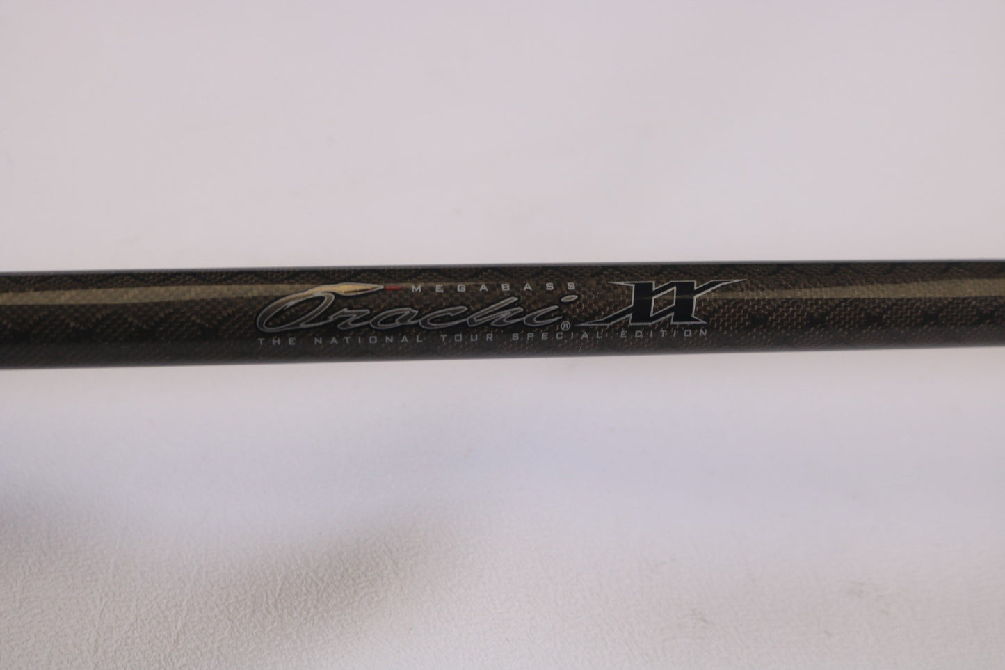 Close-up of a black carbon fiber rod, text "Megabass Orochi XX F6-70XX Tour Versatile 7'0" Heavy - Used Casting Rod - Excellent Condition" inscribed. It's perfectly preserved for high store credit in our Rod and Reel Trade-In Program, set against a white background.