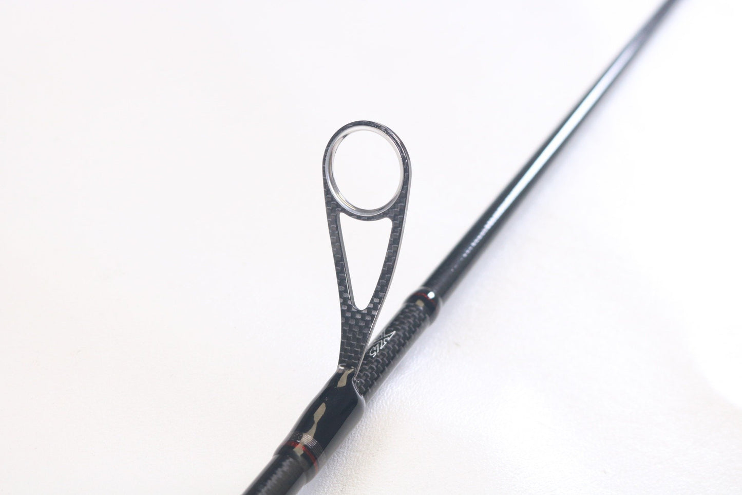 Close-up of a Daiwa Steez AGS STAGS761MMLFS The One 7'6" Medium Medium Light Used Spinning Rod in mint condition, highlighting the textured carbon fiber line guide. Ideal for those interested in top-quality used Daiwa fishing gear.