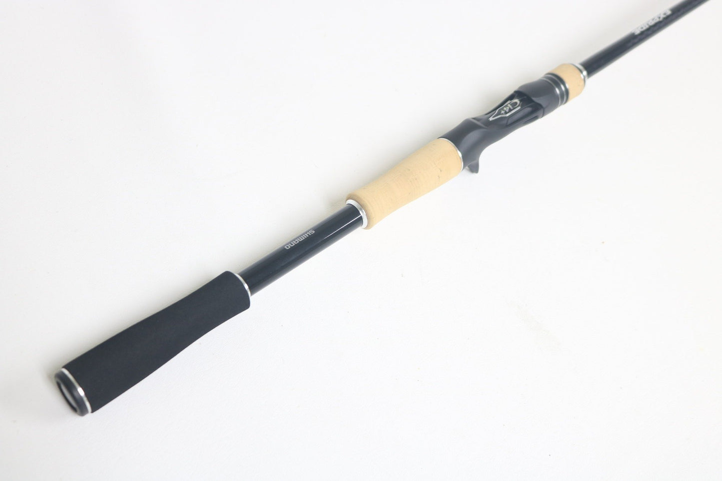 A Shimano Expride A EX172MHGA Used Casting Rod in excellent condition with a black finish and light wood and black handle, shown diagonally on a white background.