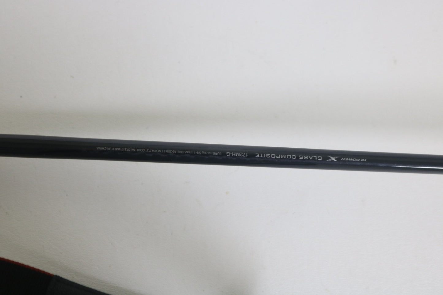 A close-up of a Shimano Expride A EX172MHGA used casting rod in excellent condition shows "GLASS COMPOSITE 7'2"MH" and "X" on its black surface, photographed against a plain white background.