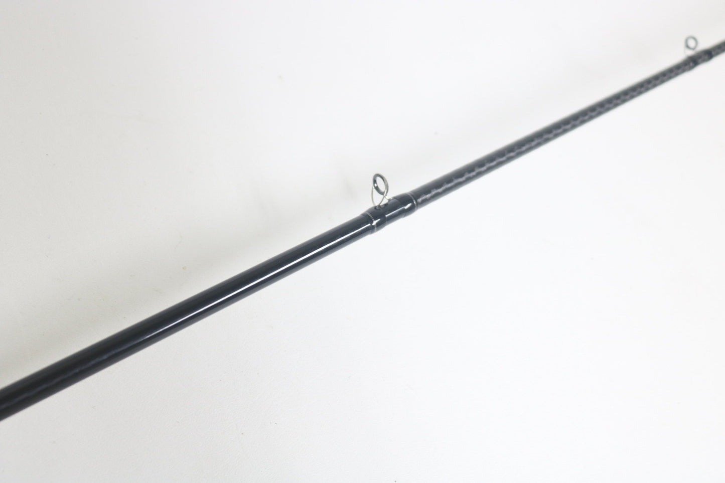 A close-up of a Shimano Expride A EX172MHGA Used Casting Rod in excellent condition, lying diagonally on a white surface, with two line guides visible.