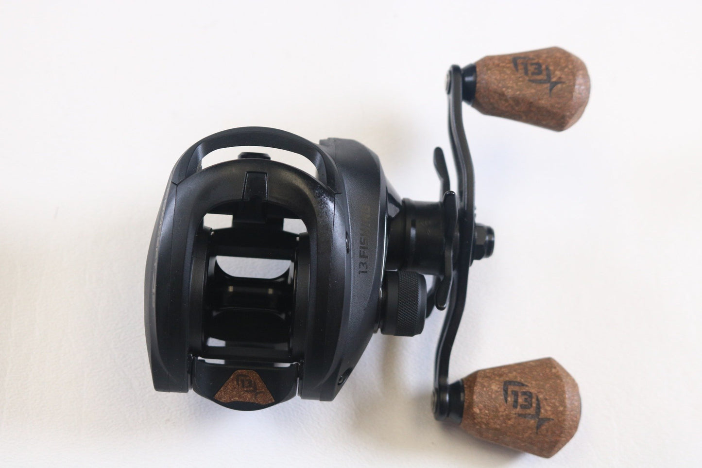 A 13 Fishing Concept A2 7.5:1 RH used baitcasting reel in excellent condition, featuring two brown cork handles and visible branding, is shown on a white background—ideal for our Rod and Reel Trade-In Program for store credit.