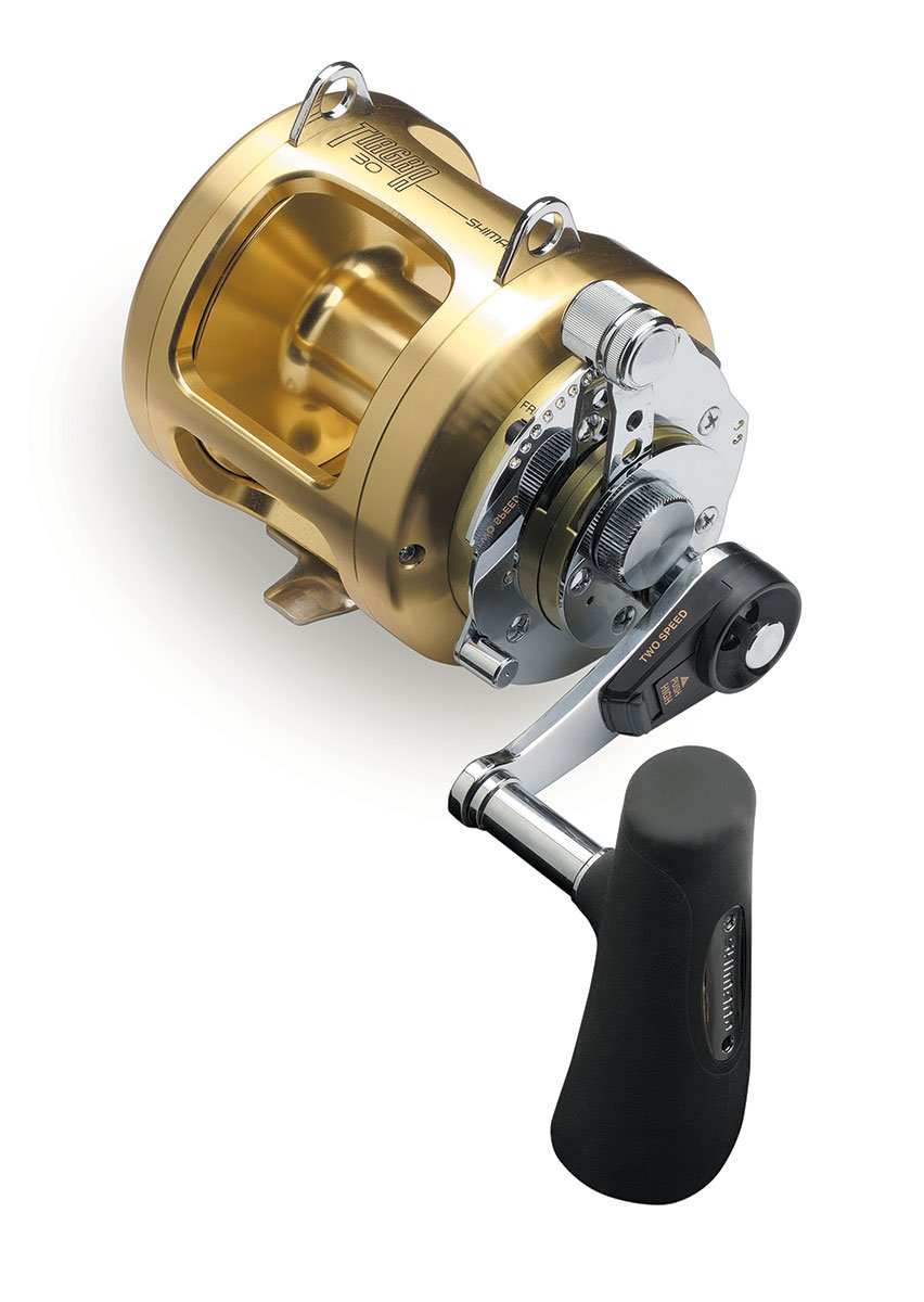 Meet the Shimano Tiagra 30A Lever Drag Reel by americanlegacyfishing, a gold and silver beauty perfect for Big Game Fishing. It features a black handle with lever drag control, intricate mechanics, and a glossy finish, showcasing the iconic "Shimano" branding on the handle's side.