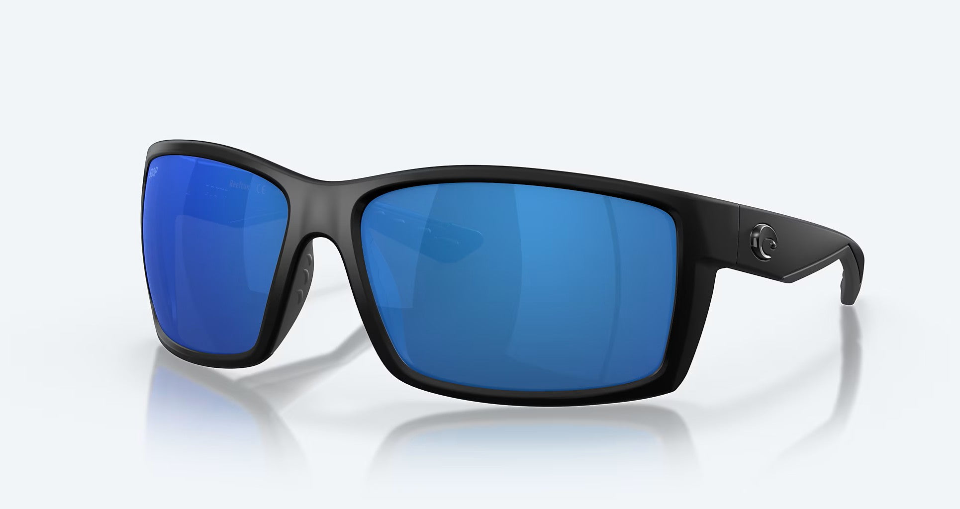 The Costa Del Mar Reefton sunglasses feature a blackout frame and large, rectangular 580P blue mirror polycarbonate lenses, displayed on a light background.
