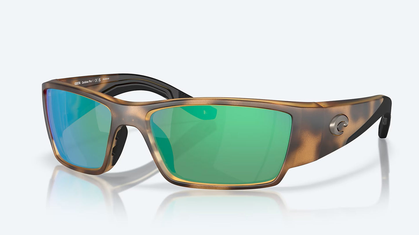 Costa Del Mar Corbina Pro sunglasses with a matte tortoise frame, 580G green mirror glass lenses, and black inner arms are displayed on a light background.
