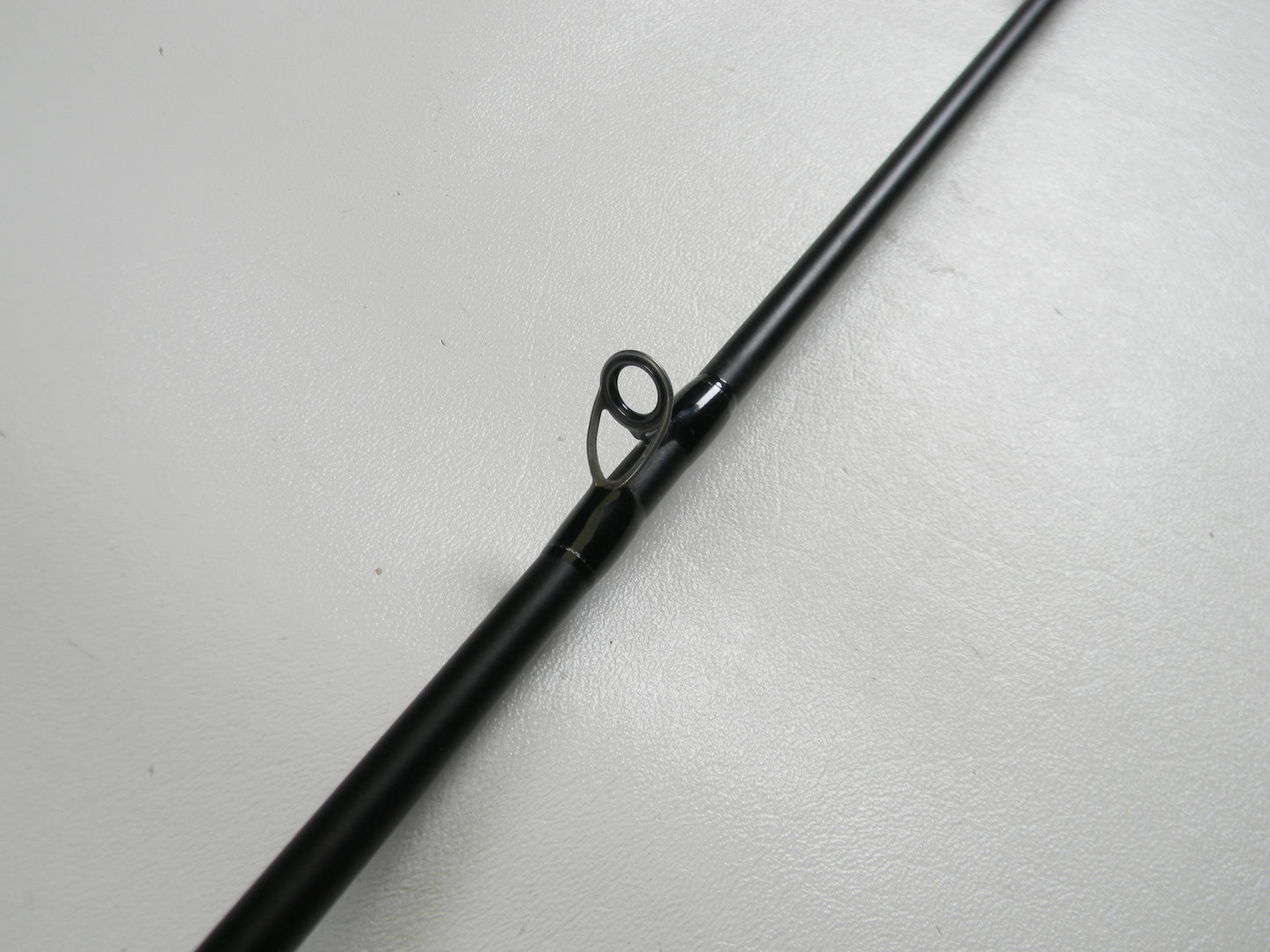 A close-up of the Dobyns Champion XP DC705CB 7'0" Medium Heavy Used Casting Rod (Excellent Condition) on a white surface, highlighting a line guide—ideal for anglers trading in gear with our Rod and Reel Trade-In Program for store credit.