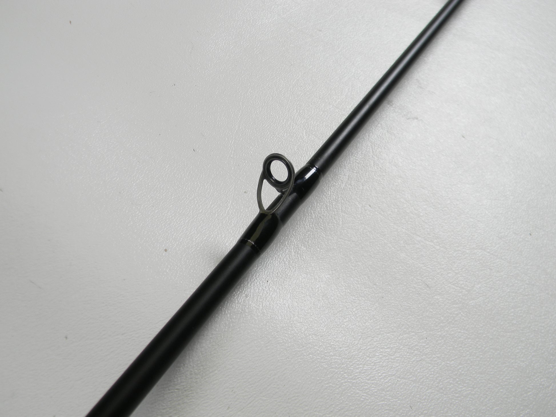A close-up of the Dobyns Champion XP DC705CB 7'0" Medium Heavy Used Casting Rod (Excellent Condition) on a white surface, highlighting a line guide—ideal for anglers trading in gear with our Rod and Reel Trade-In Program for store credit.