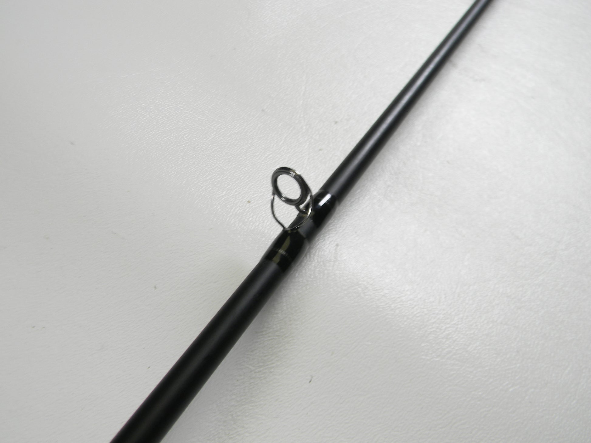 A close-up of the Dobyns Champion Gen 2 DC 704 CB 7'0" Medium Used Casting Rod in excellent condition focuses on a metal line guide, showcasing quality ideal for our Rod and Reel Trade-In Program against a white background.