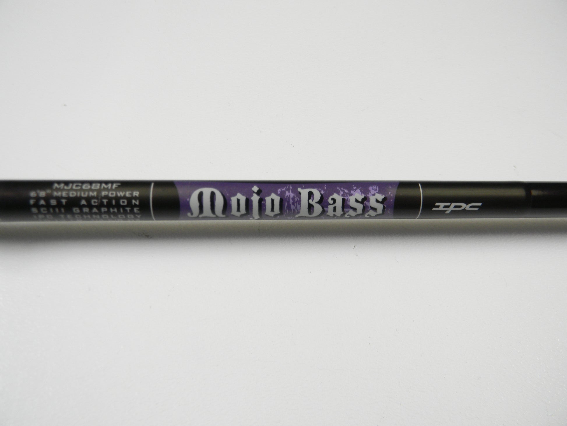 Close-up of the St. Croix Mojo Bass MJC68MF Jerkbait Casting Rod, featuring medium power, fast action, and SCIII graphite. This sleek black 6'8" rod with purple accents is part of our exclusive collection and in very good used condition.