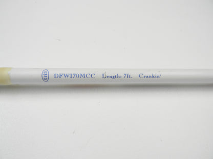 Close-up of a white Duckett rod with blue text: "DFWI70MCC Length: 7ft. Crankin'.” The used casting rod, eligible for our Rod and Reel Trade-In Program, sits on a plain white surface.