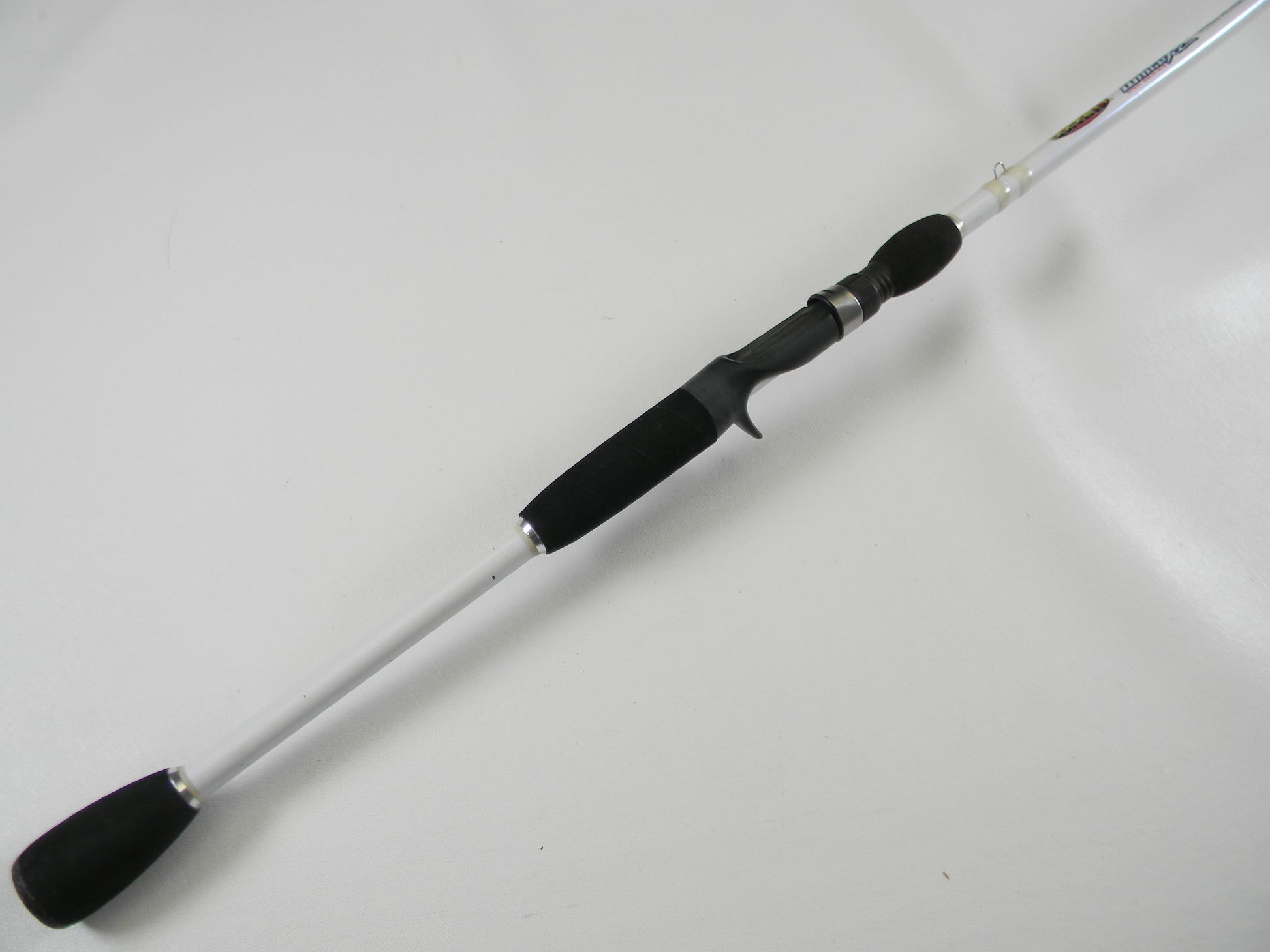 Laid diagonally on a white background, the Duckett White Ice DFWI711HC Byron Velvick 7'11" Heavy A-Rig/Swimbait used casting rod features a black handle and silver shaft. Enjoy its secure grip and metallic accents for your next catch. Trade it in through our Rod and Reel Trade-In Program for store credit.