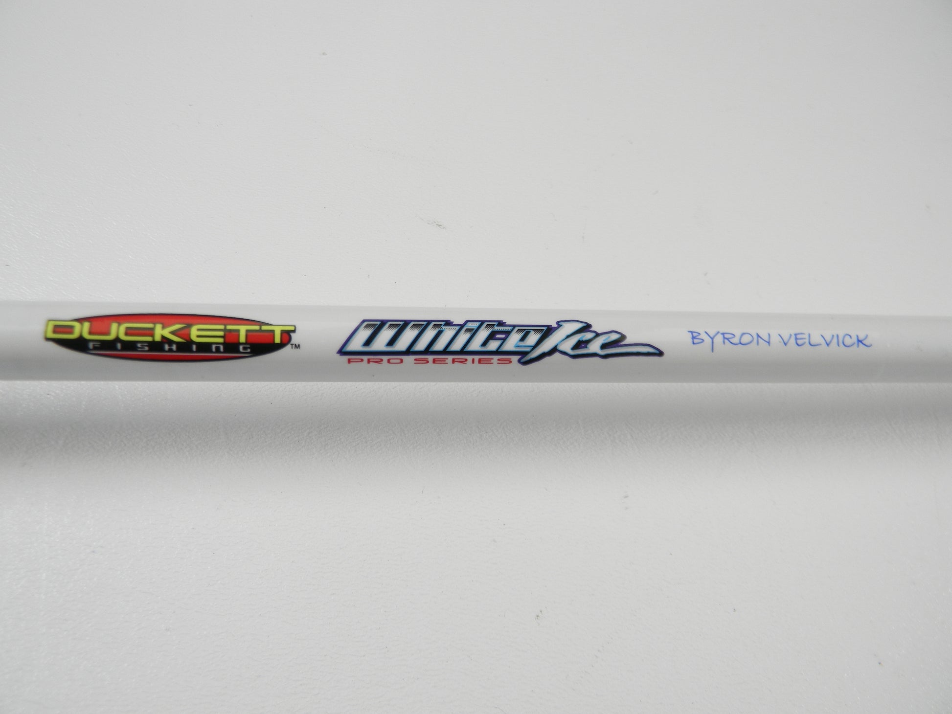 Close-up of a Duckett White Ice DFWI711HC Casting Rod, featuring "Duckett Fishing" and "White Ice Pro Series" logos, with "Byron Velvick" printed in blue on a plain white background. The rod is part of the Rod and Reel Trade-In Program.