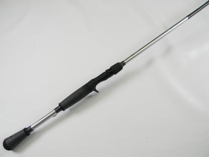 A Lew's Signature Series TLS73H Frog 7'3" Heavy casting rod, featuring a textured black grip and metallic shaft, lies diagonally against a white background. In excellent used condition, it's ideal for Rod and Reel Trade-In or those seeking exceptional quality used gear.