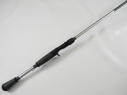 A Lew's Signature Series TLS73H Frog 7'3" Heavy casting rod, featuring a textured black grip and metallic shaft, lies diagonally against a white background. In excellent used condition, it's ideal for Rod and Reel Trade-In or those seeking exceptional quality used gear.