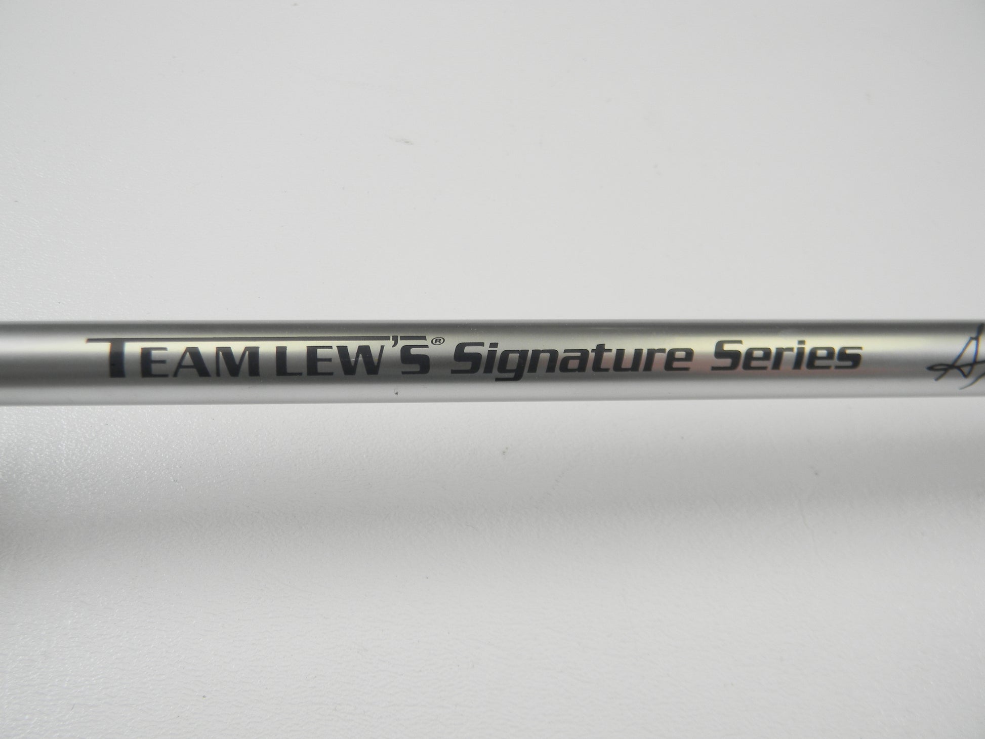 Close-up of a Lew's Signature Series TLS73H Frog 7'3" Heavy Casting Rod in excellent condition, featuring black "Team Lew's Signature Series" text on a metallic finish. Ideal for Rod and Reel Trade-In, the plain white background highlights its sleek design and pristine performance.